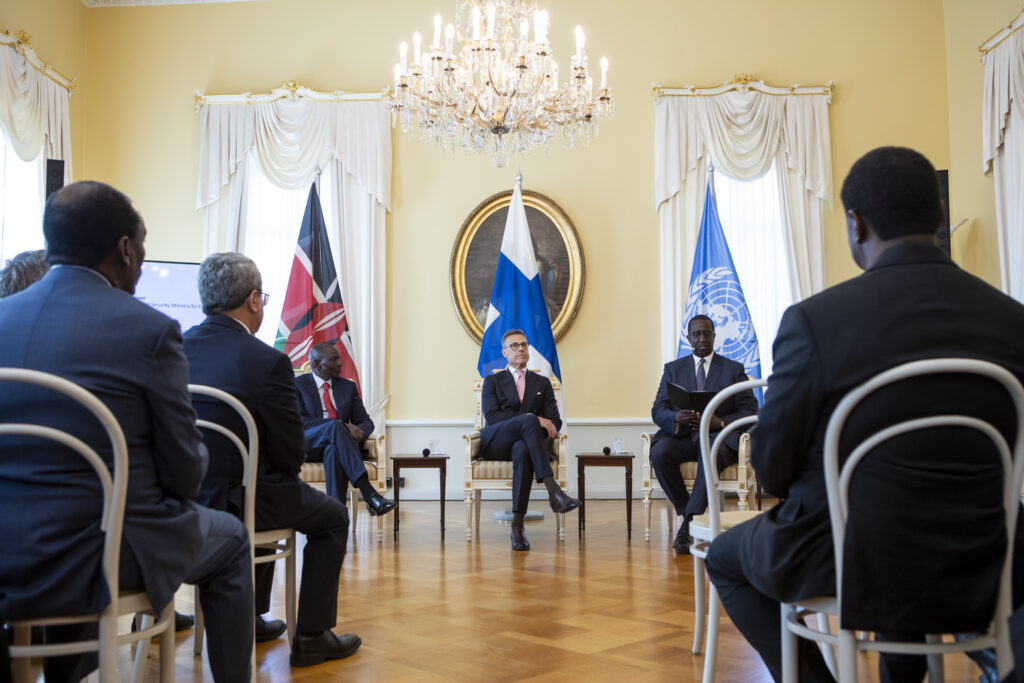 Image of three men sitting in front of a crowd